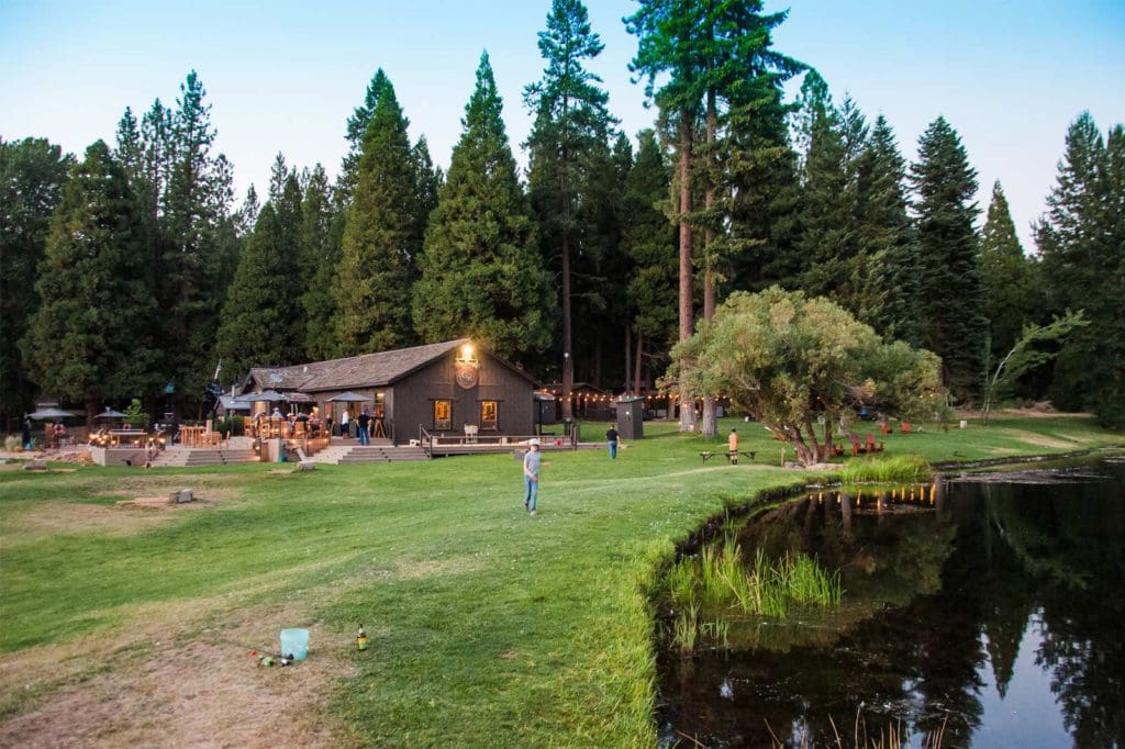 A young boy walks along a lake shore with Greenhorn Ranch resort buildings behind him.