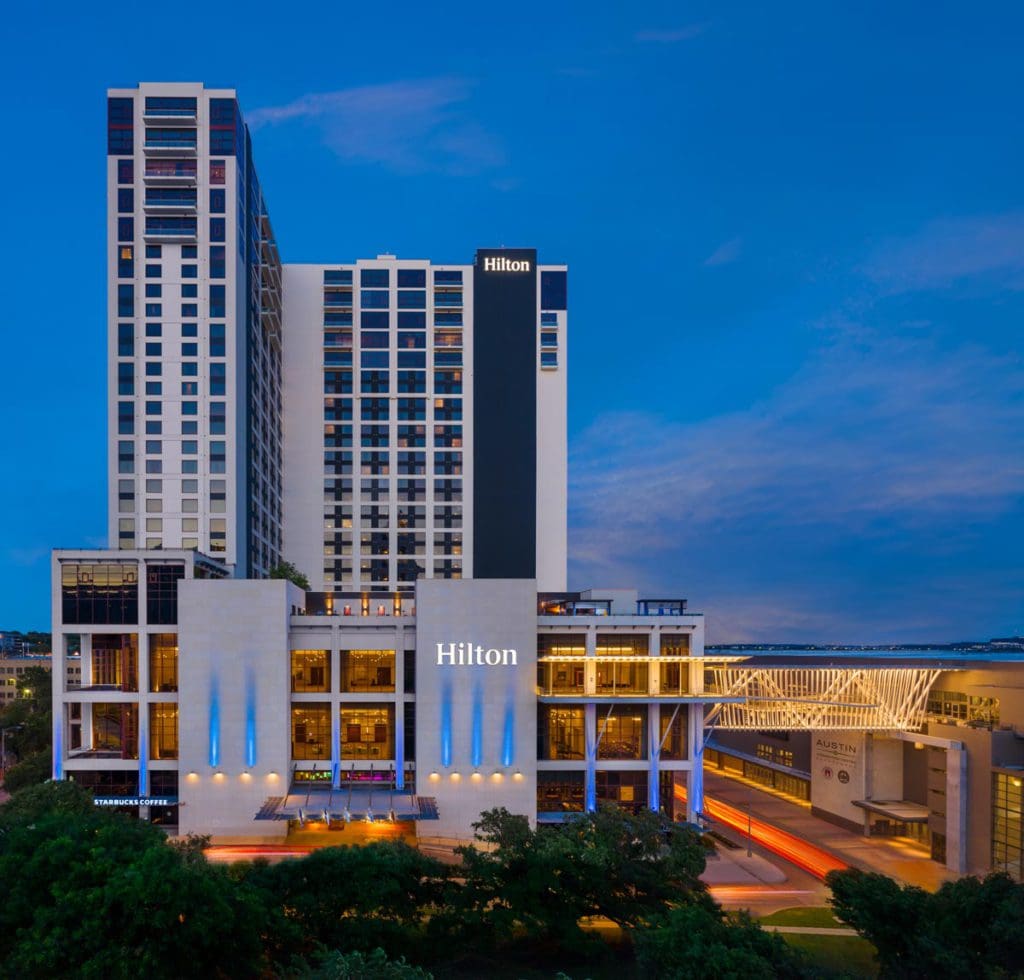 The exterior of Hilton Austin lit up at night.