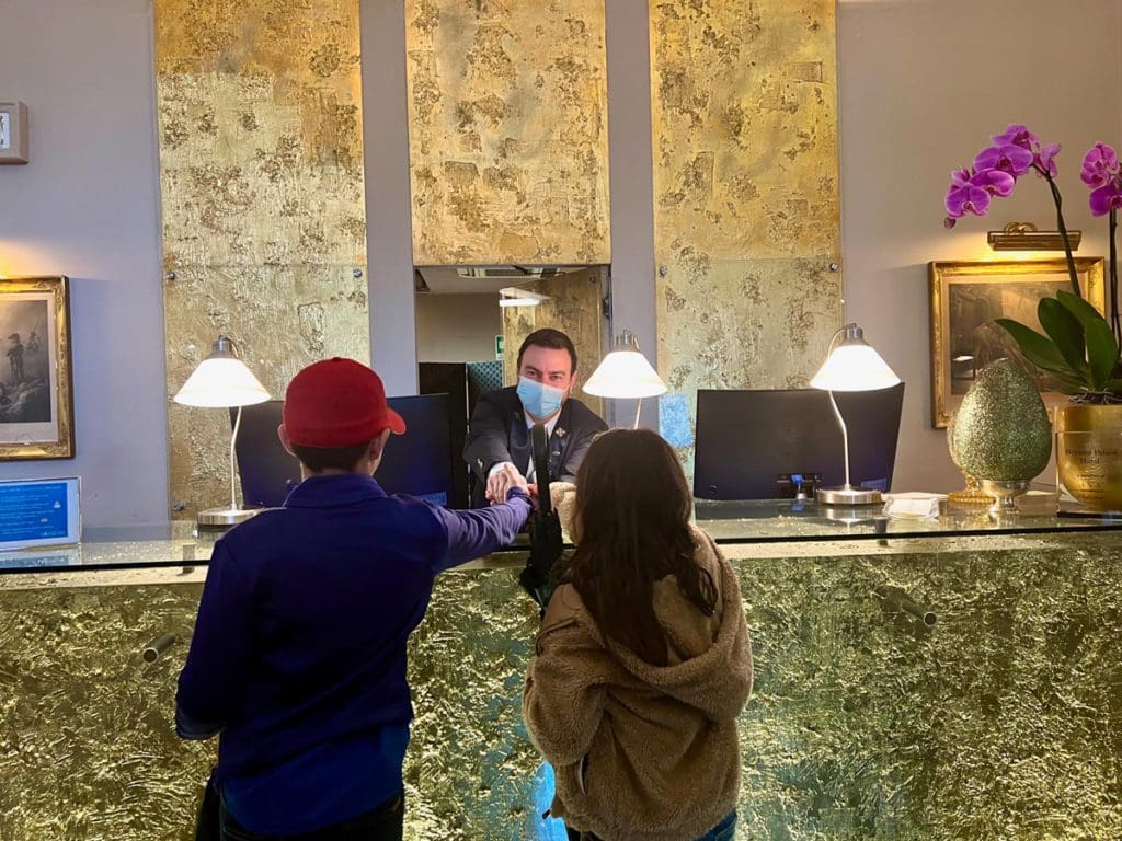 Two kids shake the hands of a concierge staff member at a hotel in Florence.