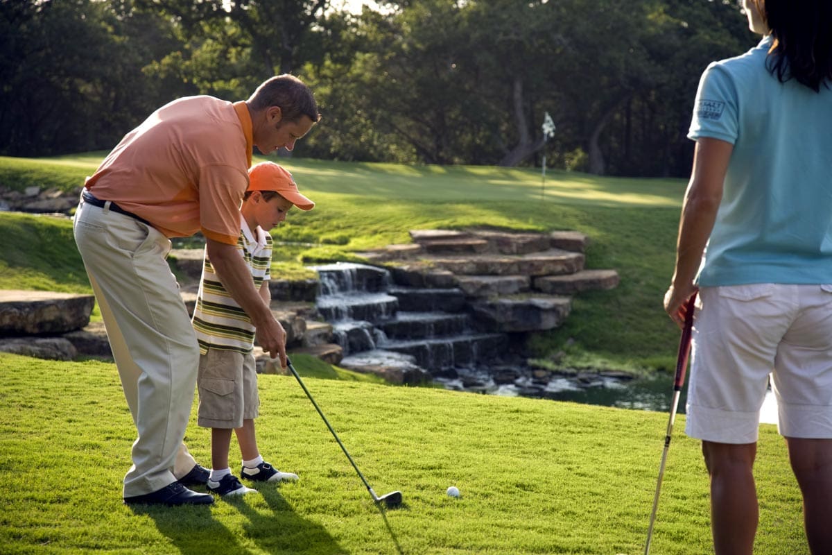 A father and young son work on their golf stroke at Hyatt Lost Pines Resort and Spa.