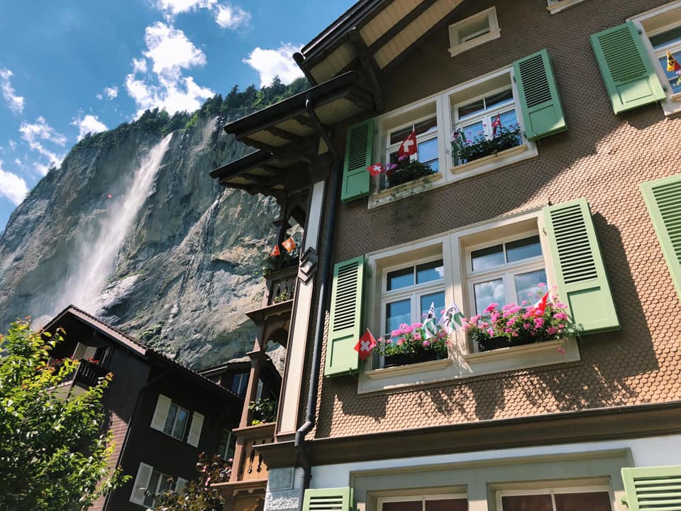 A home with traditional Swiss architecture and flower boxes in the windows in Lauterbrunnen, one of the best towns and villages to visit with your family in Switzerland.