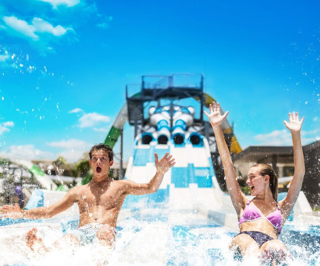 Two teens race down a waterslide at Moon Palace The Grand - Cancun, one of the best hotels in the Caribbean with a water park for families.