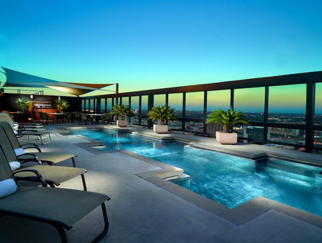 The rooftop, outdoor pool at Omni Austin Hotel Downtown overlooking the city of Austin at dusk.