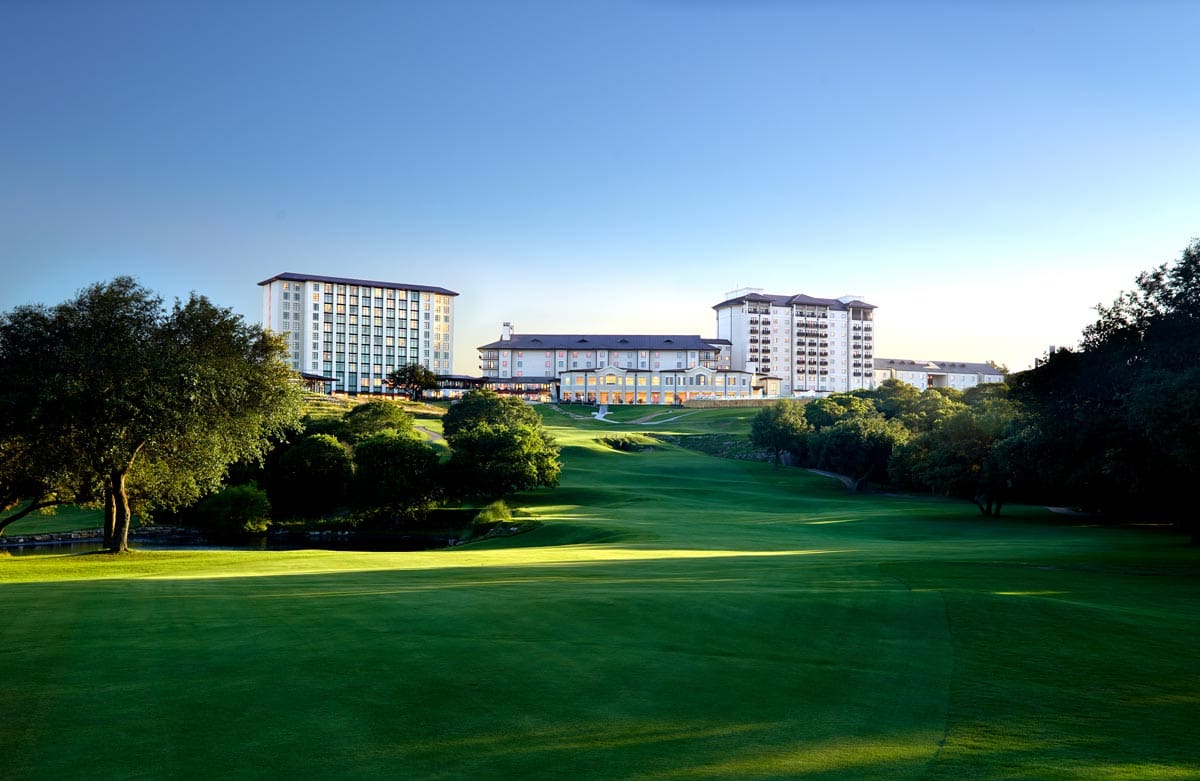 The white buildings of Omni Barton Creek Resort & Spa rise from the verdant golf course.