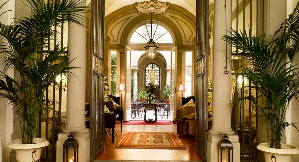 Inside the chic lobby of Relais Santa Croce by Baglioni Hotels, featuring large plants and collumns.