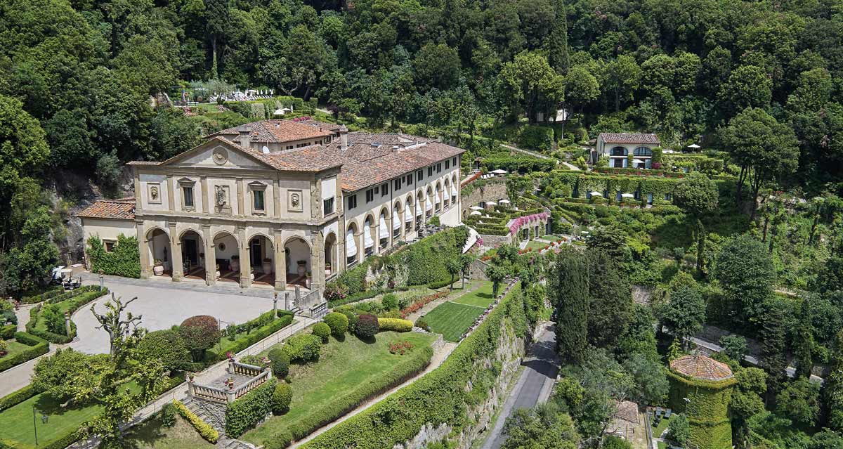 Belmond Villa San Michele standing proudly atop a hill, surrounded by lush woods.