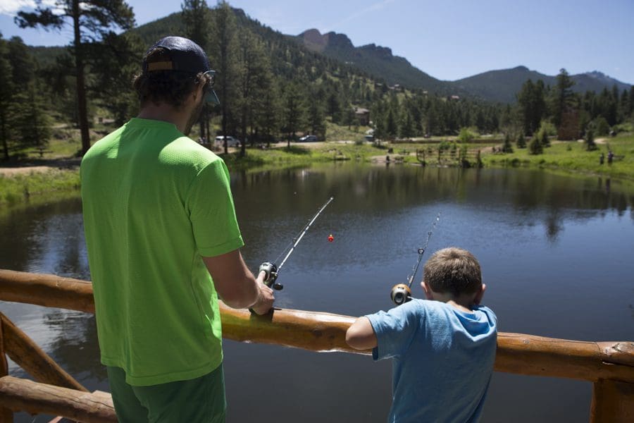 A young boy and his dad fish from a bridge over the water at YMCA of the Rockies.