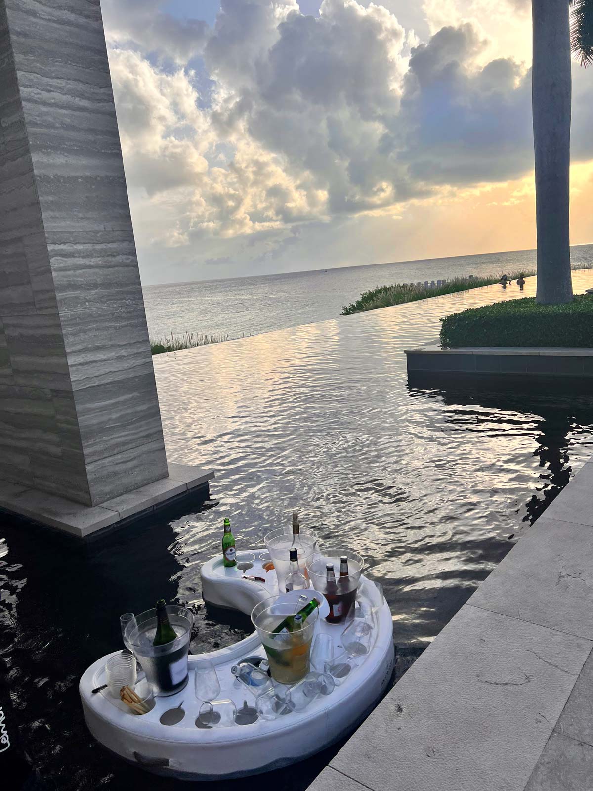 A bar extends over an adult pool at Four Seasons Resort and Residences Anguilla at dusk.