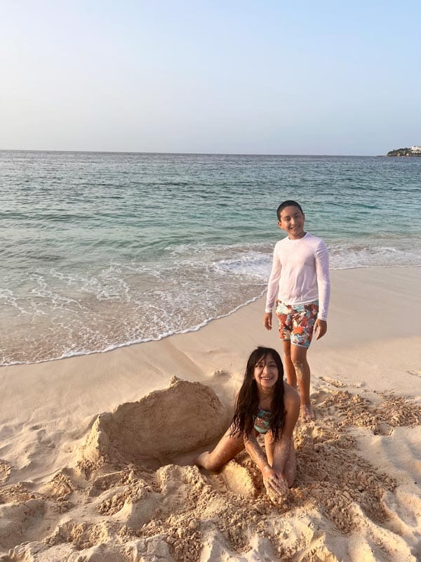 Two kids dig in the sand along the ocean on a sunny day. 