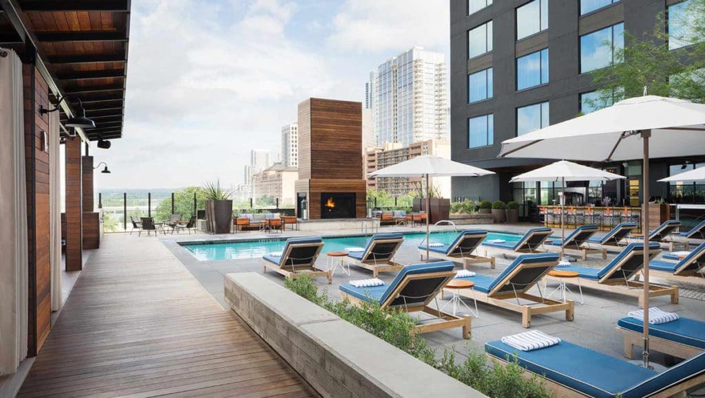 A boardwalk leading to the several rows of poolside loungers and outdoor pool at Kimpton Hotel Van Zandt.