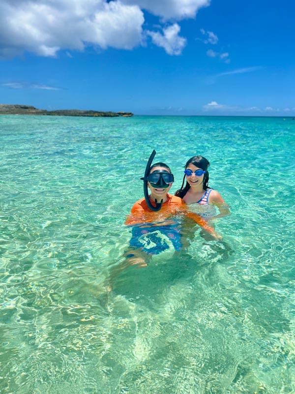 Two kids snorkel in crystal clear water offshore from Four Seasons Resort and Residences Anguilla.