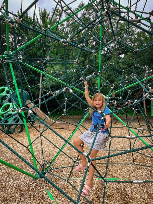 A young girl sits in a large play structure in Carson Park.