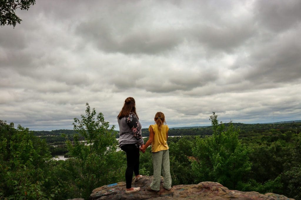 A mom and her daughter stand atop Mt. Simon, the highest point in Eau Claire, looking out toward the scenic view of the Chippewa Valley below.