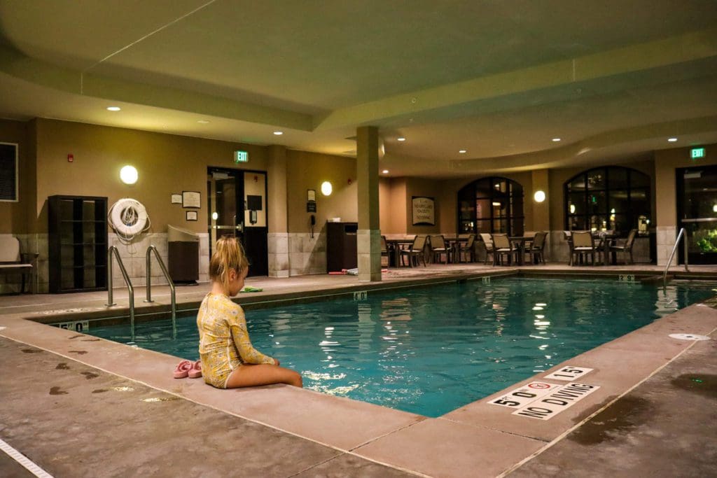 A young girl sits at the edge of a hotel pool, ready to swim.