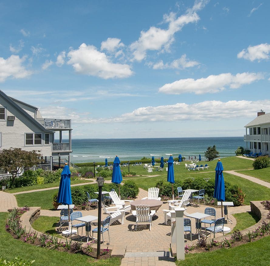A patio area surrounding a fire pit with an ocean view at Beachmere Inn.