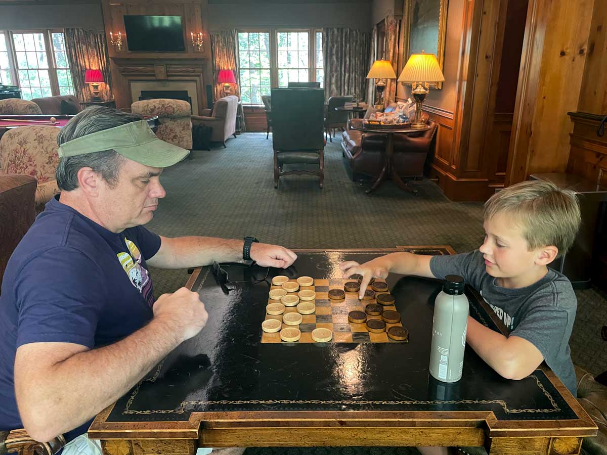 A dad and his young son play chess in the game room at Blackberry Farm.