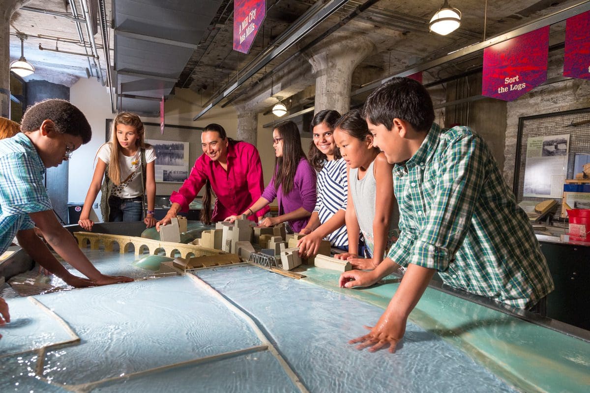 Kids and adults play in the water lab at the Mill City Museum, one of the best places to explore in the Twin Cities with kids.
