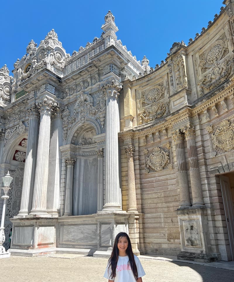 A young girl poses in front of the Dolmabahçe Palace, one of the best things to do on a family vacation to Istanbul.