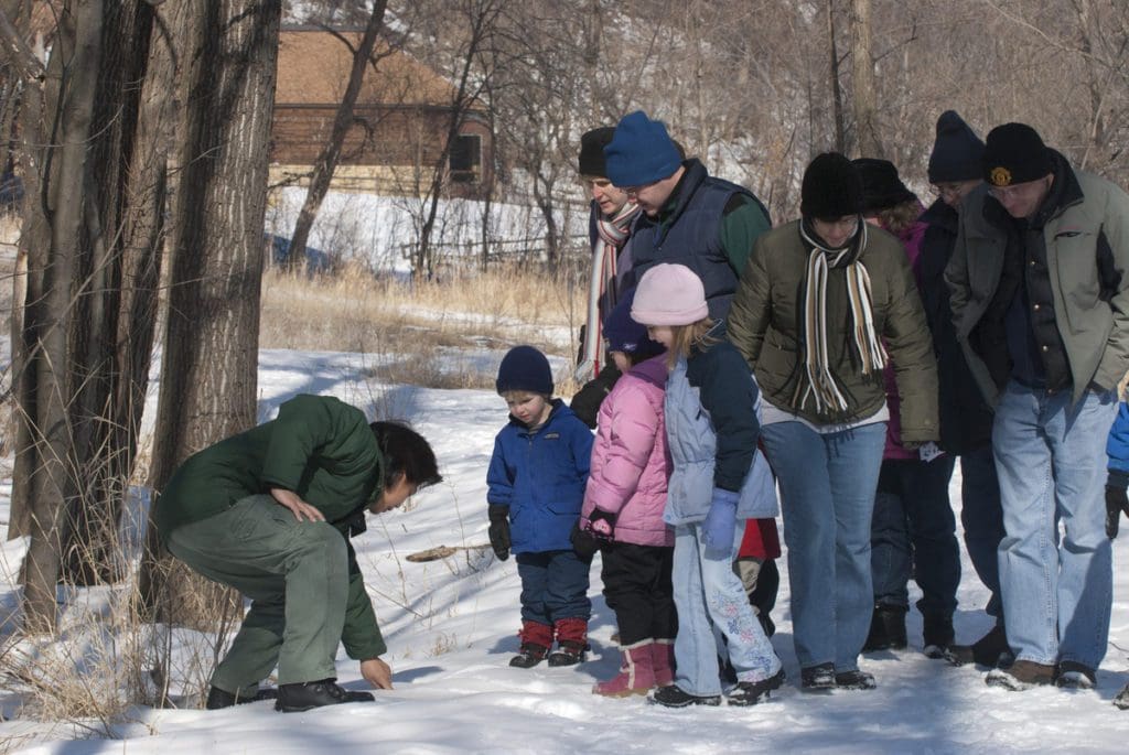 A naturalist gives a lecture to several children during a winter hike at Fort Snelling State Park.