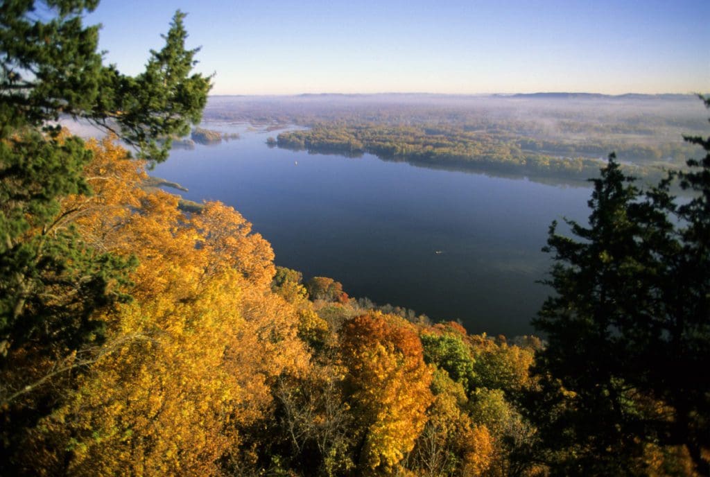 A lovely view over a bluff looking out onto a lake in the midst of fall foliage at Great River Bluffs State Park.