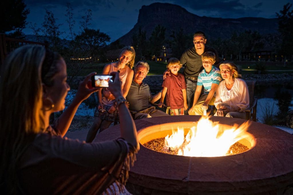 A family poses for a picture around a bon fire at Gateway Canyons Resort & Spa, one of the best eco-friendly hotels in the United States for families.