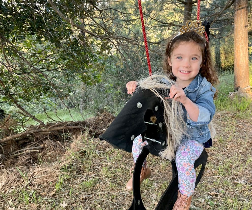 A young girl swings in a horse-themed swing while glamping.
