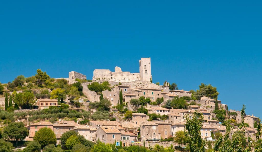 A view of the buildings of Lacoste rising atop a hill in France.