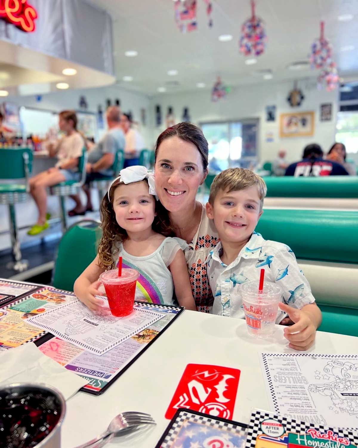 A mom and her two kids sit together at a restaurant.