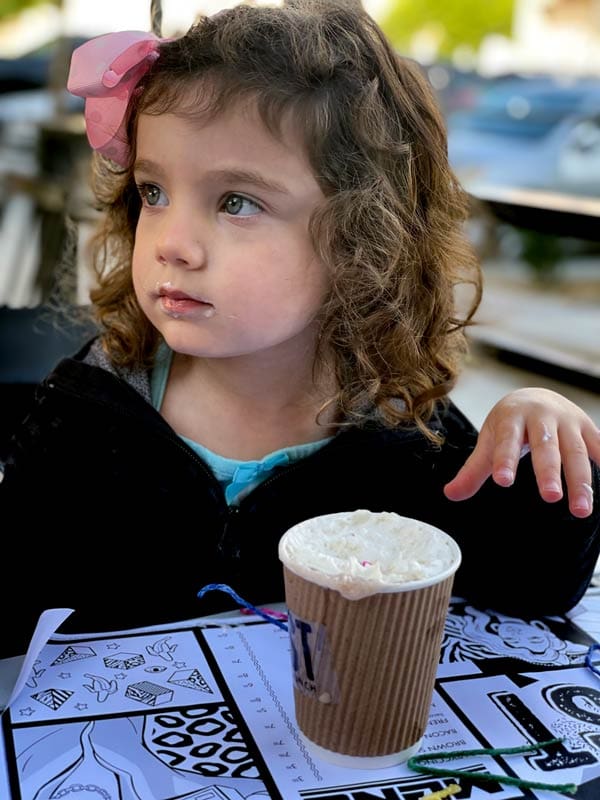 A young girl enjoys a hot chocolate with whipped cream at Toast.