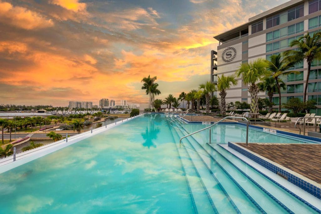 The outdoor pool at Sheraton Puerto Rico Hotel & Casino stretches along the side of the resort building at sunset.