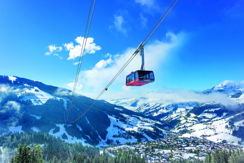 A gondola passes by overhead in the mountains near Alpendorf, Austria on a sunny ski day, a must do on your family skiing in Alpendorf itinerary.