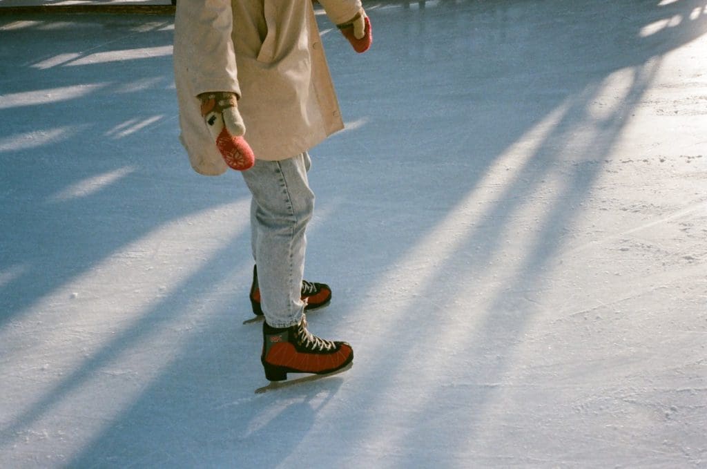 A close up of a someone's legs and feet as they ice skate around on an outdoor rink.