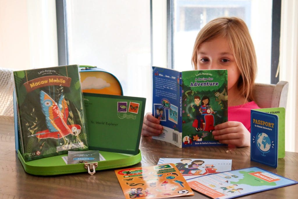 A little girl reads a book about Brazil at the kitchen table from her Little Passports subscription box.