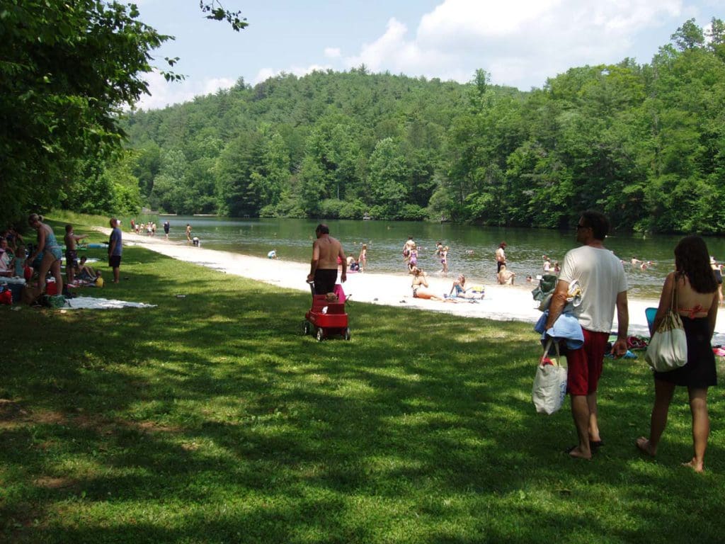 Several people mill about the shores of Cave Mountain Lake, one of the best lake destinations in Virginia with kids.