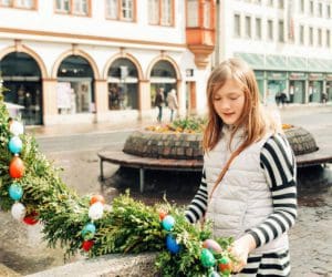 A young girl looks at a wreath covered in Easter eggs, while traveling in Europe over Easter break with her family.