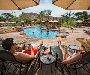 Parents enjoy a cocktail on poolside loungers, while watching their kids play in the outdoor pool at Gateway Canyons Resort & Spa.