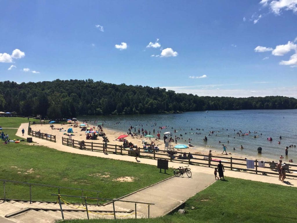 People dot a sandy beach at Lake Anna in Virginia on a sunny day, one of the best Memorial Day Weekend getaways from Washington DC for families.