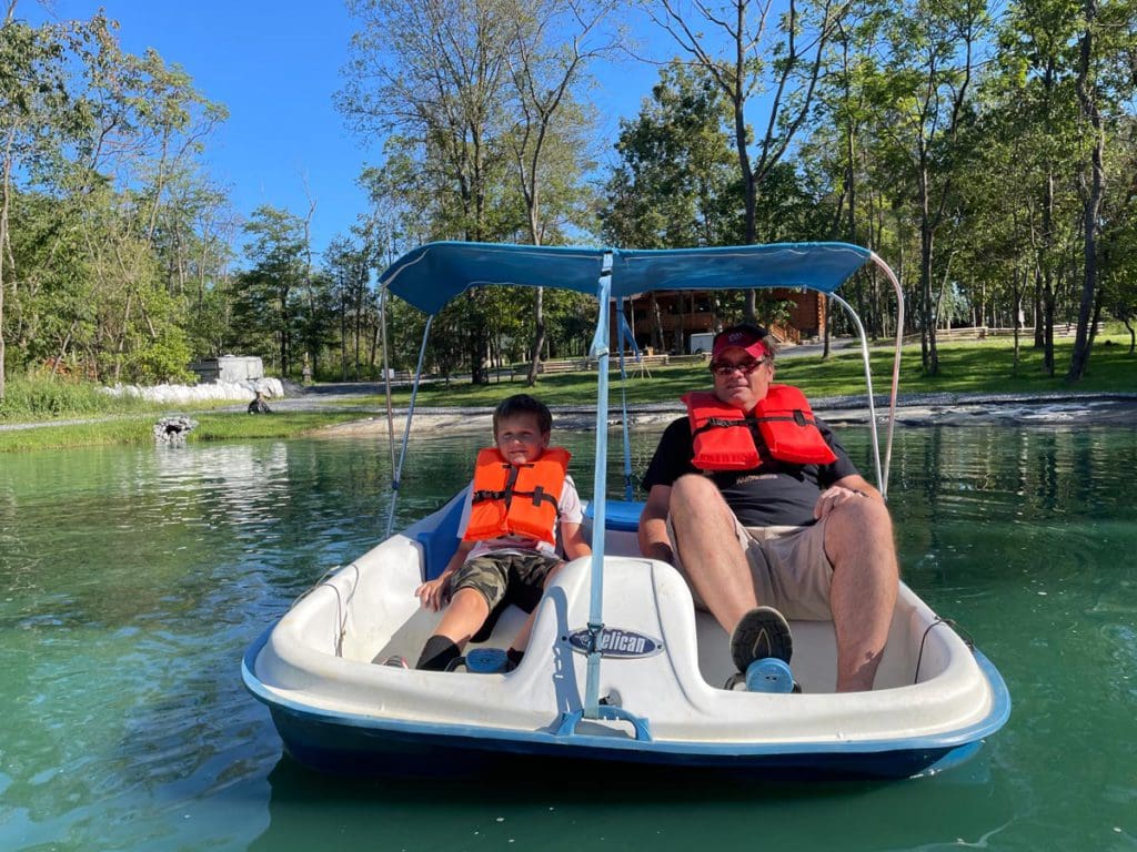 A dad and his young son paddle board on a lake in Virginia.