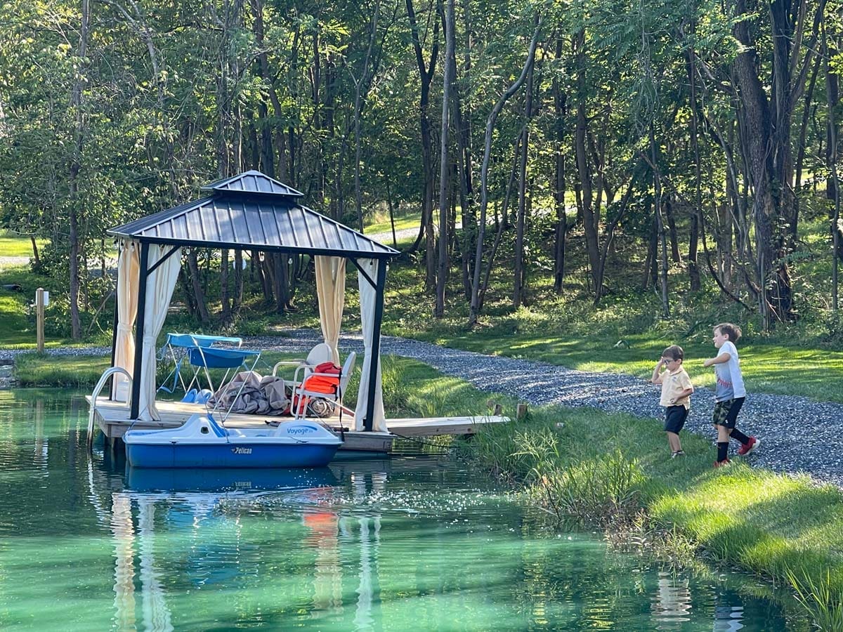 Two boys run toward a dock on a beautiful lake in Virginia, one of the best affordable summer vacations in the United States with kids.
