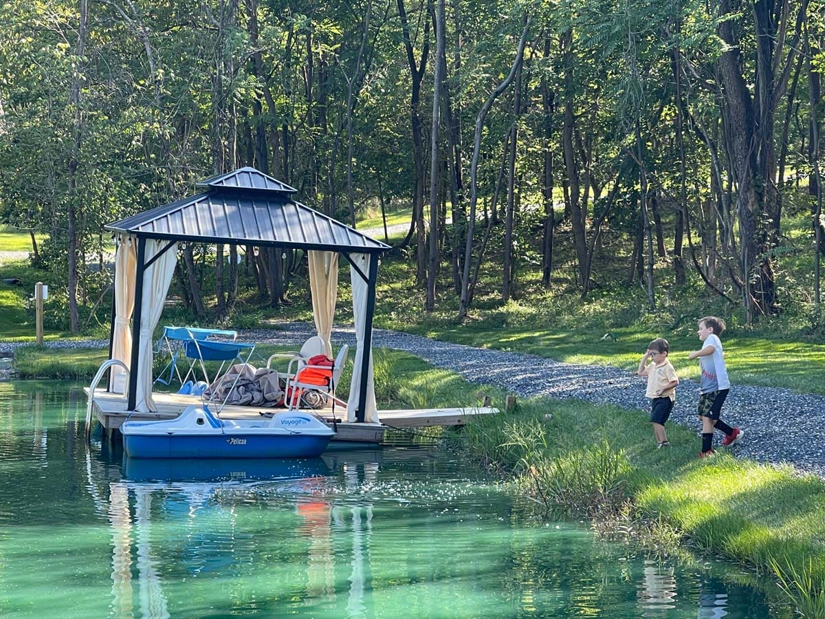 Two boys run toward a dock on a beautiful lake in Virginia, one of the best affordable summer vacations in the United States with kids.