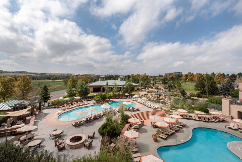 An aerial of the outdoor pools and surrounding pool deck with loungers at Omni Interlocken Hotel.