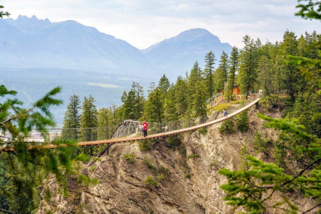 People cross a long pedestrian skybridge near Golden, BC with mountains in the distance.