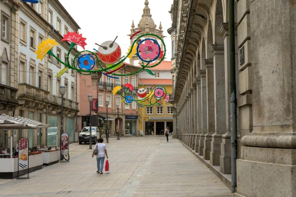 People mill through a street in Portugal, decorated for Easter at one of the best places to visit during Easter with your family.