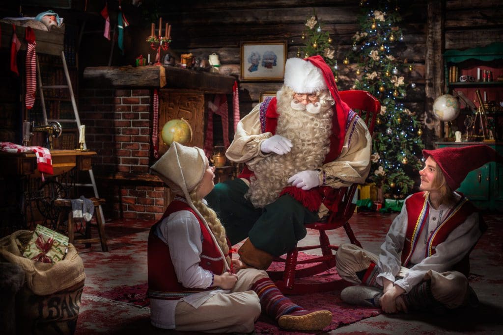 Santa and two elves discuss Christmas at SantaPark in Finland.