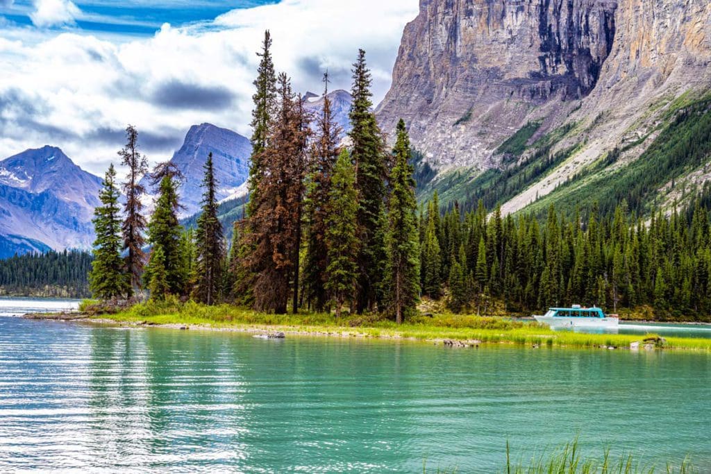 A boat moves along Maligne Lake near Spirit Island, with the Canadian Rockies in the distance.