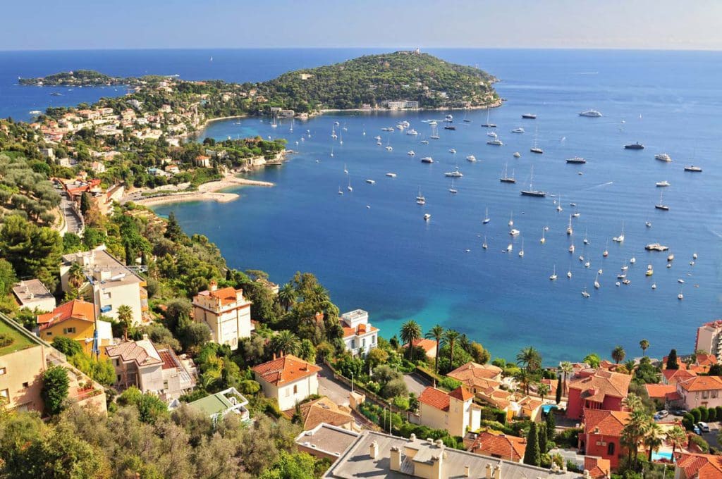 An aerial view of St. Jean Cap Ferrat along the ocean with several ships in the port.