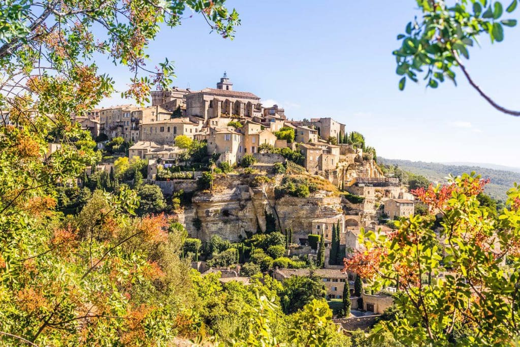 A view of Gordes through the trees, atop a hill in France.