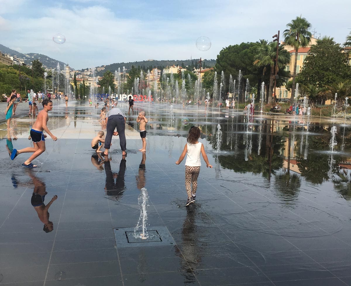 Several kids play in a splash zone in Nice, one of the best towns in the South of France with kids.