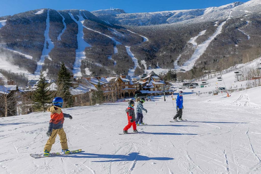 An instructor leads a few young skiers down a slope during ski school at Stowe Resort, one of the best ski resorts in the United States for families.