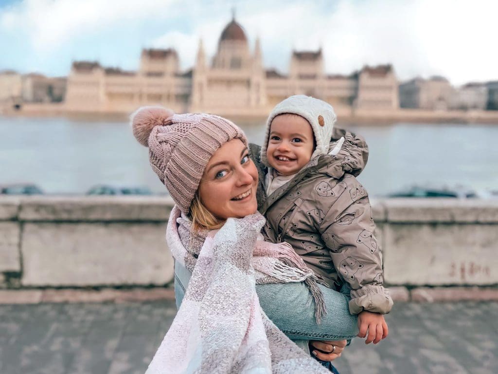 A mom holds her toddler while exploring Budapest together.